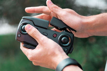 Close up of man folding drone quadcopter joystick controller. remote controlled wireless quadcopter drone with video and photo camera for aerial photographyの写真素材