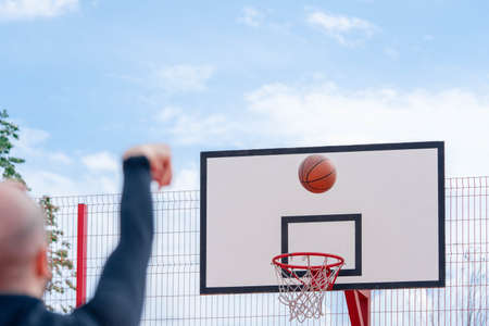 Attractive man playing basketball on basketball court. Man is out of focus and on foreground,...