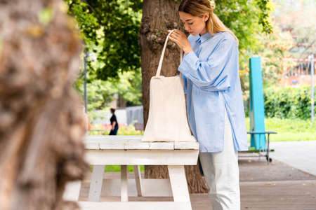 Young and attractive woman holding cotton blank white canvas bag at modern park. Eco friendly concept .eco biodegradable. Empty space. Copy space.の写真素材