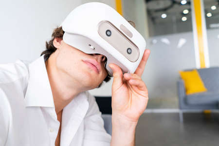 Man wearing virtual reality goggles in modern bright co-working office. the VR experience.