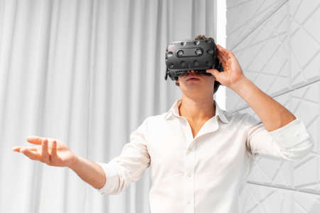 Man wearing virtual reality headset. touching air during the VR experience. goggles in modern co-working office.の写真素材