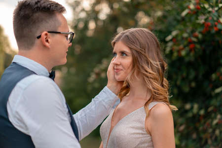 Wedding couple looking at each other with love and happiness at park at sunset time. Beautiful bride with groom. Female and male portrait.の写真素材