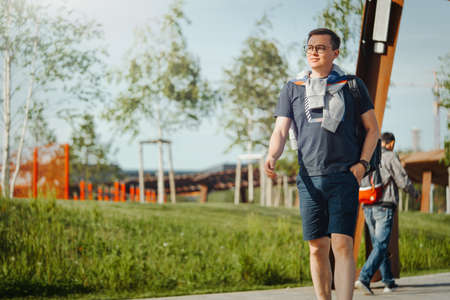 Attractive young man strolling at modern park. Man is on foreground, modern park is on background.の写真素材