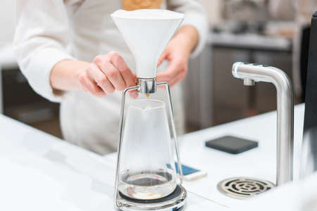 process of preparation black coffee in pour over coffee maker in bright modern cafe. Alternative ways of brewing coffee.の写真素材