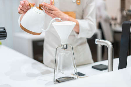 process of preparation black coffee in pour over coffee maker in bright modern cafe. Alternative ways of brewing coffee.の写真素材