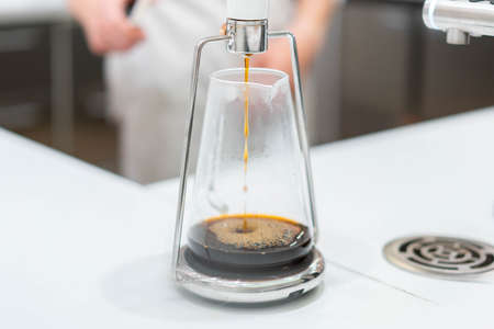 process of preparation black coffee in pour over coffee maker in bright modern cafe. Alternative ways of brewing coffee.の写真素材