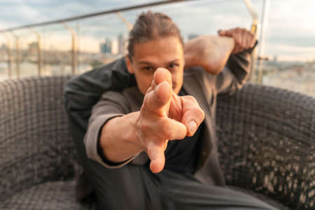 Attractive athletic man practicing yoga in business center with beautiful view on a city from skyscraper.の写真素材