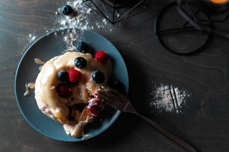 Pavlova Dessert Cake with Berries on grey Plate and wooden table. round Meringue with whipped cream, close up. Delicious Pavlova cake with fresh raspberry and blueberry.の写真素材