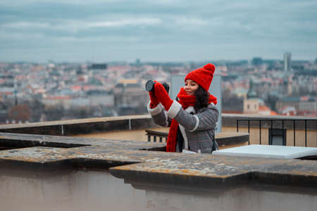 Wide Shot Of Young Beautiful Woman With Big Red Scarf Making Photos Of Romantic View To The Gothic Cityscape of Prague.の写真素材
