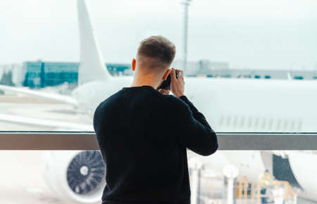 Blogger photographer making a photo of jet at runway before taking off. Concept of modern travelling and blogging.の写真素材