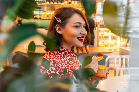 Beautiful Brunette Woman Celebrating Saint Valentine Day Alone With Cupcake In Stylish Cafe.の写真素材