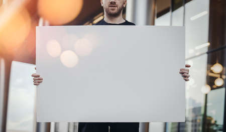 Close up Young Man Holding Blank Canvas Placard Outdoors. Activist Protesting Against Political and Social Issues. Copy Space. Empty Space. Single Person Protestの写真素材