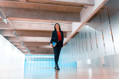 Woman With Only One Hand In Modern College Holding a Book And Smiling. Concept Of Disabled Person Living Full Life And Getting Higher Educationの写真素材