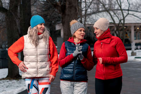 Mature Women Friends Walking In Park After Morning Run And Talking About News. Active Lifestyle at Middle Age.の写真素材