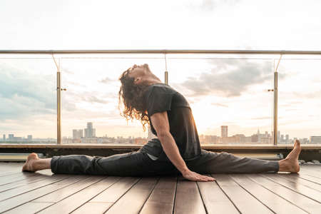 Athletic Sporty Man Doing Splits And Stretching Outdoors On Urban Background With Sunset....