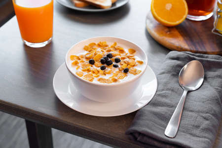 Bowl with Cornflakes, Milk and Berries on Wooden Table. Orange Juice and Honey Jar are on Background. Concept of Healthy Breakfast.の写真素材