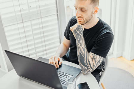 Handsome Freelancer Working On Laptop from Home In Quarantine. Protection From Coronavirus in Modern Bright Apartmentsの写真素材