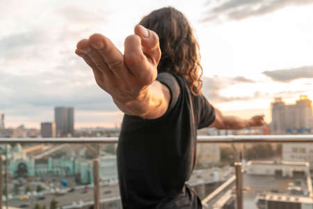 Athletic Man Meditating on Roof at Sunset And Looking At City From Above. Social Distance. Sport and Balance At Quarantine and Isolation.の写真素材