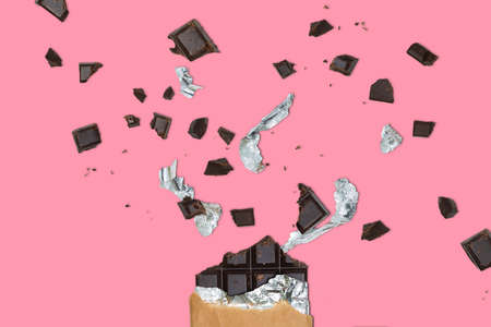 Explosion Of Chocolate on Pastel Pink Background With Chocolate Chunks and Parts of Foil. Sweet Madness. Sweet Tooth. Addiction. Creative Illustration of Milk Chocolate. Waves of Chocolate Blocksの写真素材