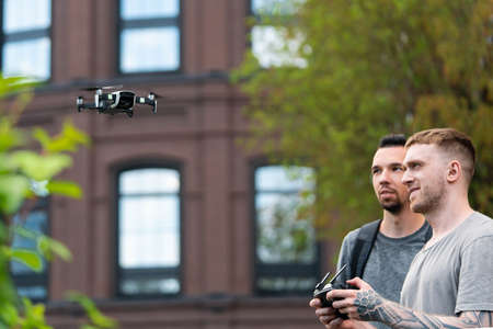 Two Young Handsome Men Launching Drone Quadcopter at Urban Stlilysh Contemporary Cityscape. Modern...