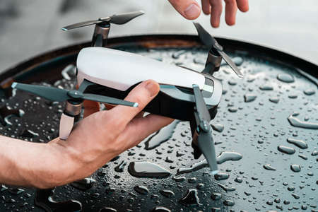 Close up of Man Holding Black Drone Quadcopter at Black Wet Metalllic Background. Remote Controlled Wireless Quadcopter Drone With Video and Photo Camera. Minimalism Conceptの写真素材