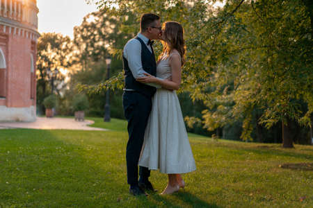 Young Couple Kissing At Green Lawn After Wedding With Sunset on Background.の写真素材