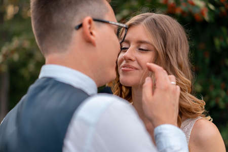 Close up Of Bride Face And Groom Hand Touching Her Face With Tender. Wife Looking AT Husband With Love and Adoration. Wedding Ceremony At Parkの写真素材