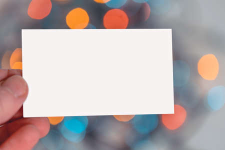 Blank White Business Card Hold By Man Hand on Christmas Garland Background. Festive Mood And Vibesの写真素材