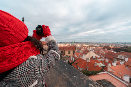 Young woman with big red scarf taking photos of old townの写真素材