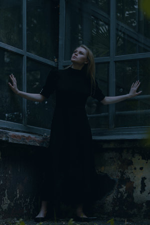 Beautiful Elegant Lady Near Abandoned Houseplant At Gothic Park. Concept Of Doubts, Confusion, and Lonelinessの写真素材