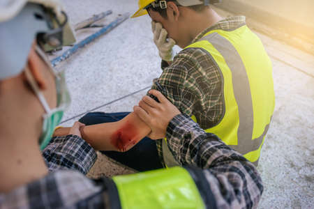 First aid for arm injuries. Builder accident in site work. Emergency service. First aid procedure.の写真素材