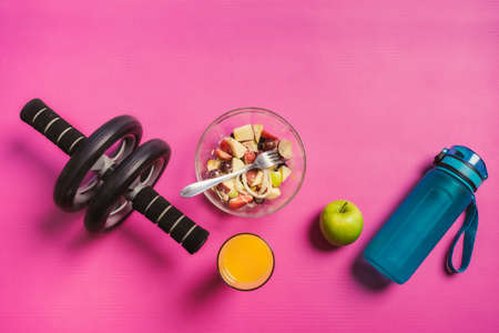 Healthy food fitness and wheel fitness equipment on pink yoga mat. Health care, exercise concept.の写真素材