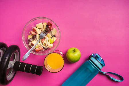 Healthy food fitness and wheel fitness equipment on pink yoga mat. Health care, exercise concept.の写真素材