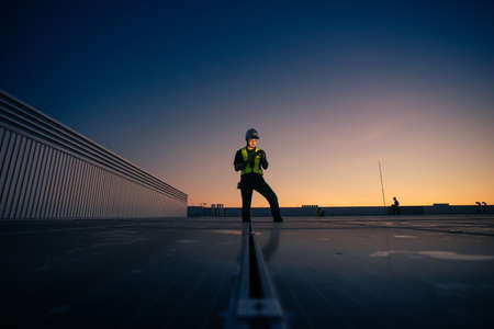 Asian man engineer service check installation solar cell on the roof of factory on the morning. Silhouette technician with solar cell on the roof of factory under morning sky. Technology solar cell.の写真素材