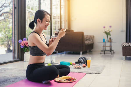 Healthy Asian woman happy smiling in sportswear eating healthy breakfast. Eating diet and exercise relaxation concept.の写真素材