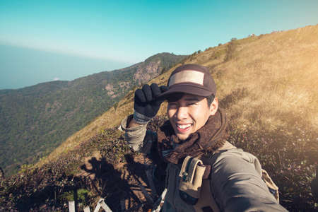 Asian man traveller happy smiling take a selfie on the mountain.の写真素材