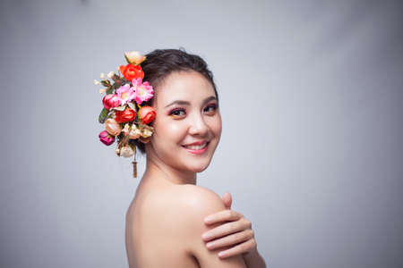 Portrait of beautiful young asian woman with flowers. Brunette woman with luxury makeup. Perfect skin. Eyelashes. Cosmetic eyeshadow. Perfect Creative Make up and Hair Style.の写真素材