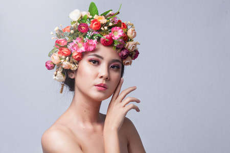 Portrait of beautiful young asian woman with flowers. Brunette woman with luxury makeup. Perfect skin. Eyelashes. Cosmetic eyeshadow. Perfect Creative Make up and Hair Style.の写真素材