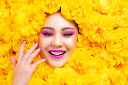Colorful fashion makeup Asian woman happy smile with yellow flower.の写真素材