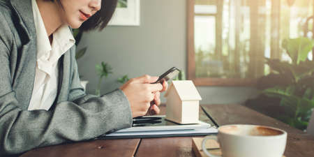 Asian businesswoman real estate agent using smartphone for contract working at table in coffee shop.の写真素材