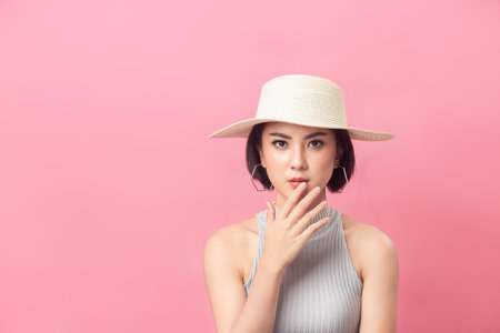 Asian woman short hair wearing hat in studio pink background.の写真素材
