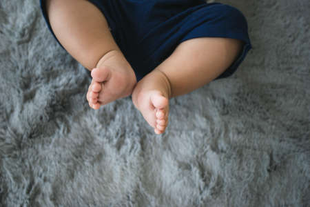 New born baby feet on grey carpet, chubby leg adorable of child.