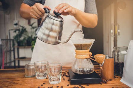 Person holding kettle pour hot water over the coffee powder. Making filter coffee. Drip coffee.の写真素材