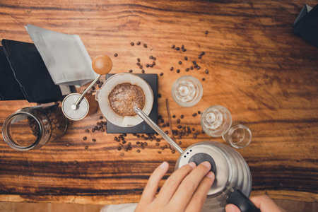Top view barista holding kettle pour hot water over the coffee powder. Making filter coffee. Drip coffee.の写真素材