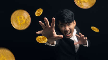 Businessman jumping grab bitcoin levitates. Asian man with bitcoin flying on black background.