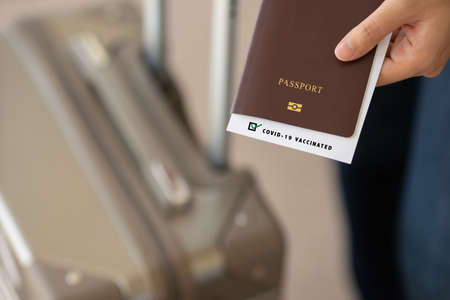 Selective focus, Passport on hand holding with Covid-19 vaccinated label. Travel concept during Covid-19 pandemic.の写真素材