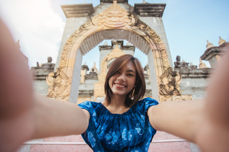 Young Asian woman happy smile selfie with attractions pagoda of the buddhism. Trip travel in southeast Asia after pandemicの写真素材
