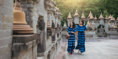 Two Asian woman traveler in blue dress walking travel together. Trip travel in pagoda ancient of Asia.の写真素材