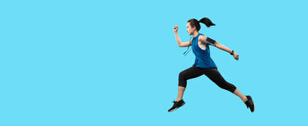 Clipping path young Asian active woman running and jumping isolated in studio on banner light blue color background. Isolated healthy women in sportswear workout sprinting.の写真素材