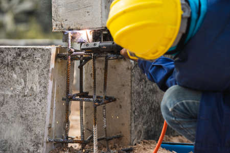 Selective focus welding. Welder working welding assembly structure between ground beam and pillar...